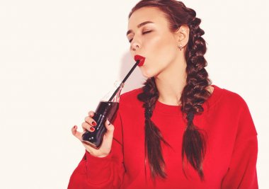 Mutlu gülümseyen kadın model parlak makyaj ve renkli dudakları ile iki boynuzu ve güneş gözlüğü üzerinde beyaz izole kırmızı yaz giysileri ile. Saman ile cam şişe soda içme