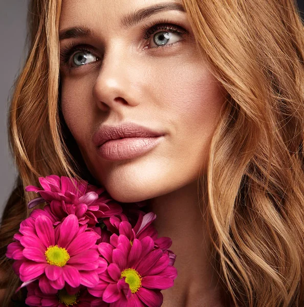 自然化粧品で若い金髪女性モデルとスタジオでポーズをとって明るい深紅色の花の完全な皮膚の美容ファッションの肖像画 — ストック写真