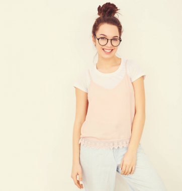 Genç güzel esmer kadın kız modeli renkli yaz pembe hipster giysileri duvara yakın poz çıplak makyaj ile portresi. Mutlu bir şekilde kamera arıyorum ve deli gidiyor 