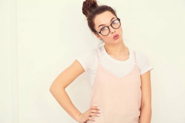 Genç güzel esmer kadın kız modeli renkli yaz pembe hipster giysileri duvara yakın poz çıplak makyaj ile portresi. Gidiş deli ve veren hava öpücük 