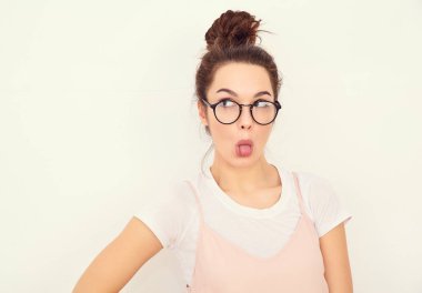 Genç güzel esmer kadın kız modeli renkli yaz pembe hipster giysileri duvara yakın poz çıplak makyaj ile portresi. Delirmek ve dilini gösteren