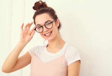 Genç güzel esmer kadın kız modeli renkli yaz pembe hipster giysileri duvara yakın poz çıplak makyaj ile portresi. Mutlu bir şekilde kamera arıyorum ve deli gidiyor 