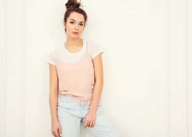 Genç güzel esmer kadın kız modeli renkli yaz pembe hipster giysileri duvara yakın poz çıplak makyaj ile portresi. Mutlu bir şekilde kamera arıyorum ve deli gidiyor 