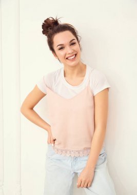 Genç güzel esmer kadın kız modeli renkli yaz pembe hipster giysileri duvara yakın poz çıplak makyaj ile portresi. Mutlu bir şekilde kamera arıyorum ve deli gidiyor 