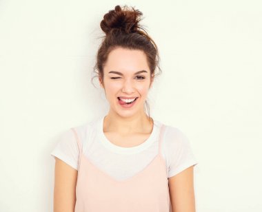 Genç güzel esmer kadın kız modeli renkli yaz pembe hipster giysileri duvara yakın poz çıplak makyaj ile portresi. Göz kırpıyor ve dilini gösteren