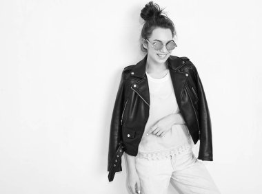 Genç güzel esmer kadın kız modeli ile çıplak makyaj duvara yakın poz güneş gözlüğü yaz hipster motorcu deri ceket elbise giyiyor portresi. Delirmek 