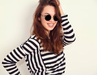 Genç güzel esmer kadın kız modeli yaz hipster giysiler ve güneş gözlüğü duvara yakın poz çıplak makyaj ile portresi. Delirmek 