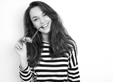 Genç güzel esmer kadın kız modeli yaz hipster giysileri duvara yakın poz çıplak makyaj ile portresi. Gidiş deli ve ısırma güneş gözlüğü 