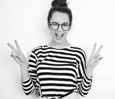 Yaz hipster giysileri duvara yakın poz çıplak makyaj ile genç güzel esmer kadın kız modeli portresi gözlük. Göz kırpıyor ve barış işareti gösterilen