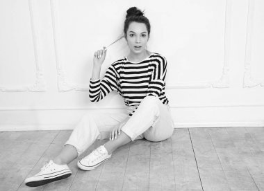 Genç güzel esmer kadın kız modeli yaz hipster giysileri duvara yakın poz çıplak makyaj ile portresi. Katta oturan