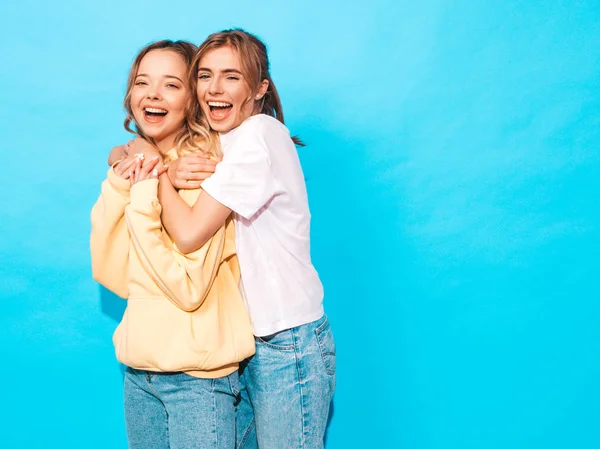 两个年轻美丽的微笑的金发嬉皮士女孩在时尚夏天五颜六色的 T恤衣服 性感无忧无虑的女人摆在蓝色的墙壁附近 有乐趣的积极的模型 — 图库照片