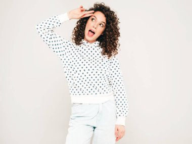 Kıvırcık saçlı, güzel bir mankenin portresi yaz hippi kıyafetleri giymiş, gri arka planda poz veren kaygısız bir kız. Son moda komik ve pozitif kadın.