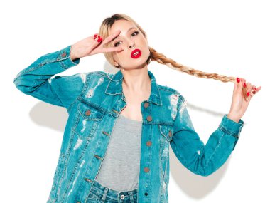Genç, güzel hippi kötü kız portresi moda kotlar içinde, yaz kıyafetleri ve burnunda küpe. Stüdyoda poz veren kaygısız, güler yüzlü, sarışın kadın. Eğlenceli bir model.