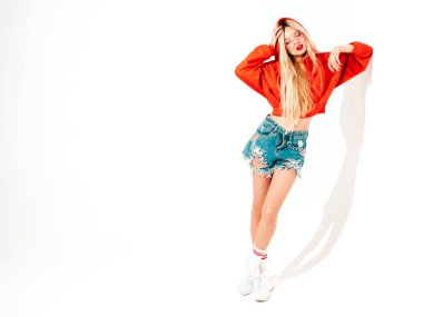 Moda kırmızı kapüşonlu kötü kız ve burnunda küpe olan genç güzel hippi portresi. Stüdyoda poz veren kaygısız, güler yüzlü sarışın kadın. Pozitif model. Beyazlar üzerinde izole edilmiş. 