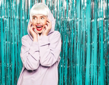 Beyaz peruklu ve kırmızı dudaklı genç seksi hippi kız. Yaz kıyafetleri içinde güzel, modaya uygun bir kadın. Stüdyoda mavi parlak parlak arka planda poz veren tasasız bir model.