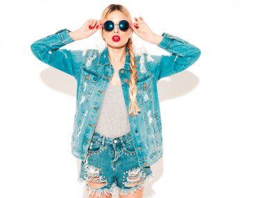 Genç, güzel, hippi kötü kız portresi moda kotlar içinde, yaz kıyafetleri içinde ve burnunda küpe ile stüdyoda poz veren kaygısız, güler yüzlü sarışın kadın. Pozitif model eğleniyor.