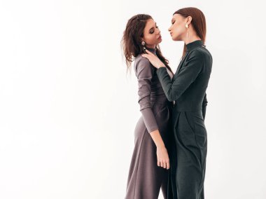 Stüdyoda beyaz duvarın yanında poz veren kaygısız kadınlar. Parlak makyajlı moda mankenler. Sarılıp birbirlerine dokunuyorlar.