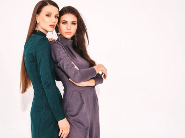 Stüdyoda beyaz duvarın yanında poz veren kaygısız kadınlar. Parlak makyajlı moda mankenler. Sarılıp birbirlerine dokunuyorlar.