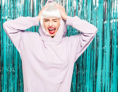 Beyaz peruklu ve kırmızı dudaklı genç seksi hippi kız. Yaz kıyafetleri içinde güzel, modaya uygun bir kadın. Stüdyoda mavi parlak parlak arka planda poz veren tasasız bir model.