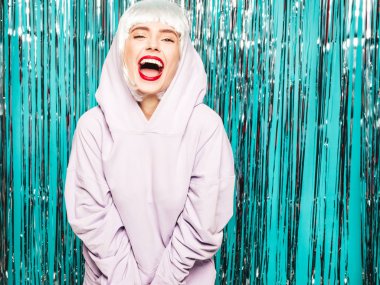 Beyaz peruklu ve kırmızı dudaklı genç seksi hippi kız. Yaz kıyafetleri içinde güzel, modaya uygun bir kadın. Stüdyoda mavi parlak parlak arka planda poz veren tasasız bir model.