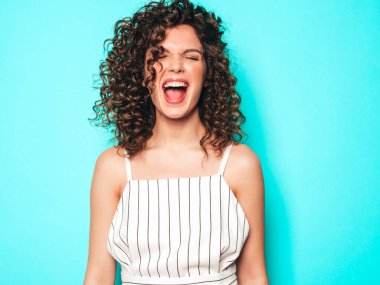Portrait of beautiful smiling model with afro curls hairstyle dressed in summer hipster clothes.Sexy carefree girl posing near blue wall.Trendy funny and positive woman