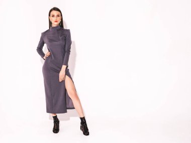 Stüdyoda beyaz duvarın yanında poz veren şık yaz elbiseli güzel esmer kız. Parlak akşam makyajlı, modaya uygun bir model.