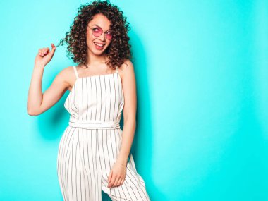 Portrait of beautiful smiling model with afro curls hairstyle dressed in summer hipster clothes.Sexy carefree girl posing near blue wall.Trendy funny and positive woman