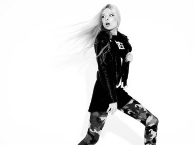 Siyah deri ceketli ve şık daracık asker pantolonlu genç güzel bir hippi kız. Burnunda küpe olan bir model. Stüdyoda yürüyen ve zıplayan bir kadın.