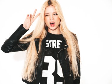 Genç, güzel, hippi, siyah deri ceketli, şık, daracık asker pantolonu giymiş kötü kız. Burnunda küpe olan bir model. Stüdyoda poz veren kaygısız bir kadın.