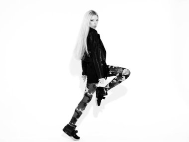 Siyah deri ceketli ve şık daracık asker pantolonlu genç güzel bir hippi kız. Burnunda küpe olan bir model. Stüdyoda yürüyen ve zıplayan bir kadın.