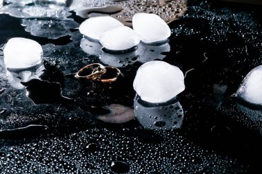 Alyanslar krom kaplama bir yüzeyde. Işığın yansımalarıyla su damlaları. Odaklanma. Kuyumcu için reklam fotoğrafı. Su kabarcıkları