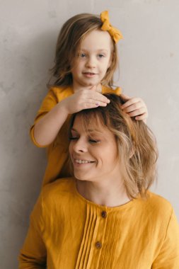 Çamaşır elbiseli anne ve kız dönüyor, gülüyor ve eğleniyorlar.