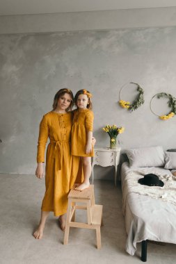 Çamaşır elbiseli anne ve kız dönüyor, gülüyor ve eğleniyorlar.