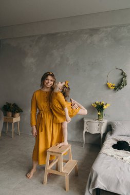 Çamaşır elbiseli anne ve kız dönüyor, gülüyor ve eğleniyorlar.