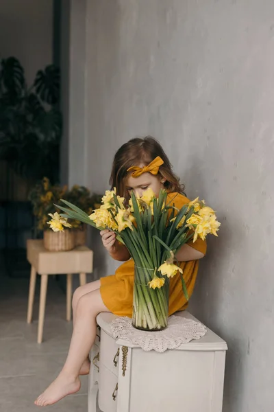 little girl in a yellow dress with a beautiful bouquet of narcissus flower