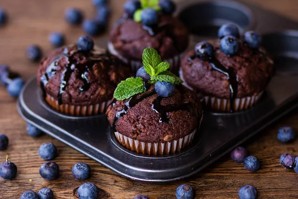 Choklad muffins med choklad, blåbär och mynta i en trä bakgrund — Stockfoto