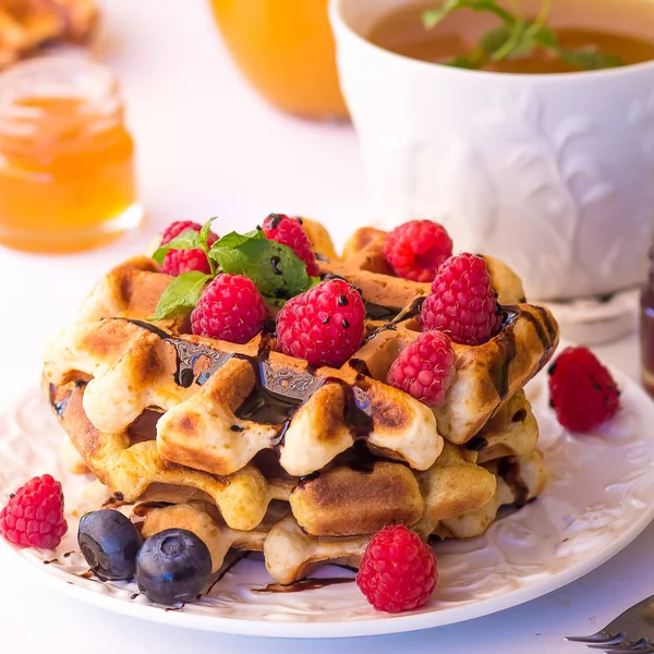 Belgische Waffeln mit Himbeeren, Schokolade und Sirup auf einem Teller. — Stockfoto