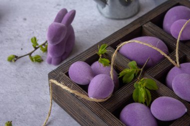 Ahşap bir kutuda mermer Paskalya yumurtaları, samandan bir yatakta, mor yapraklı erik ağacının çiçekli dalları.