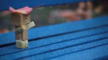 El yapımı ahşap figür sonbahar yaprağı bankta yağmur görüntüsü 