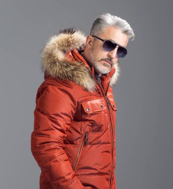 Adam maduro posando con parka de plumas naranja.