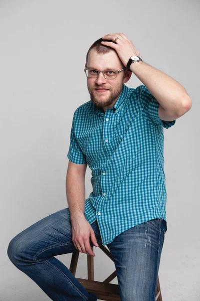 Junger Mann mit Brille sitzt weißen Hintergrund — Stockfoto