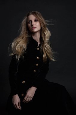 Siyah elbise koyu arka plan üzerinde oturan poz modelde tam uzunlukta