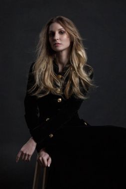 Siyah elbise koyu arka plan üzerinde oturan poz modelde tam uzunlukta