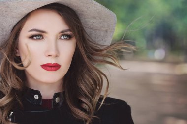Muhteşem Model kadın bir şapka açık havada. Rüzgarlı kıvırcık saçları ve Mak