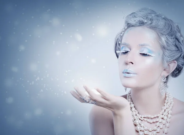 Mujer de invierno modelo de moda soplando nieve por la noche. Nieve reina chica sobre fondo azul con estrellas, nieve y purpurina — Foto de Stock