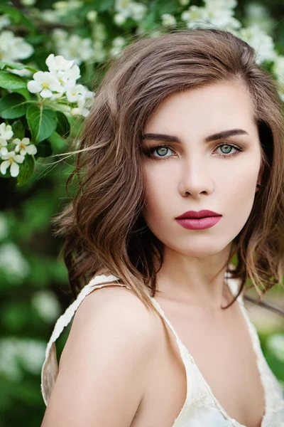 Vacker kvinna med vågigt hår på våren Blossom bakgrund — Stockfoto