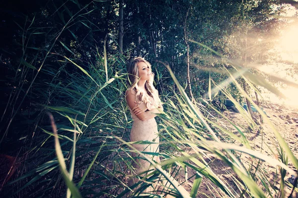 Vacker kvinna i grönt gräs och Sunligth utomhus — Stockfoto