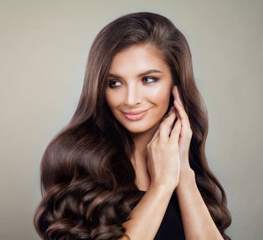 Hoş bir kadınla Kahverengi kıvırcık saç ve makyaj arka plan üzerinde