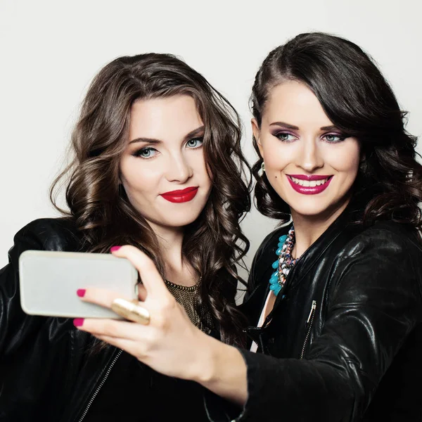Chicas felices amigas con teléfono celular sonriendo y tomando selfie — Foto de Stock
