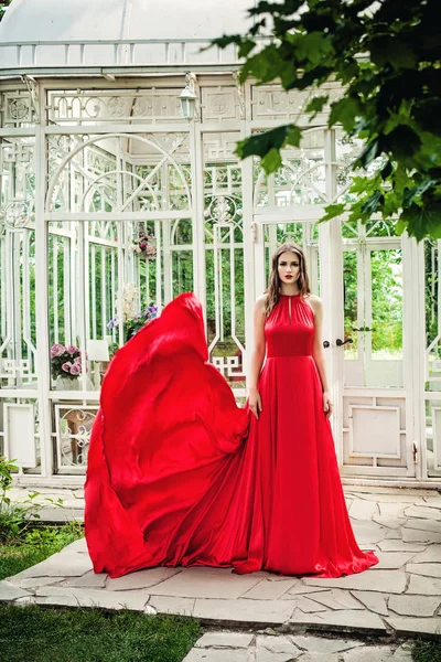 Kırmızı gece elbisesi açık havada bahar bahçe içinde güzel kadın — Stok fotoğraf